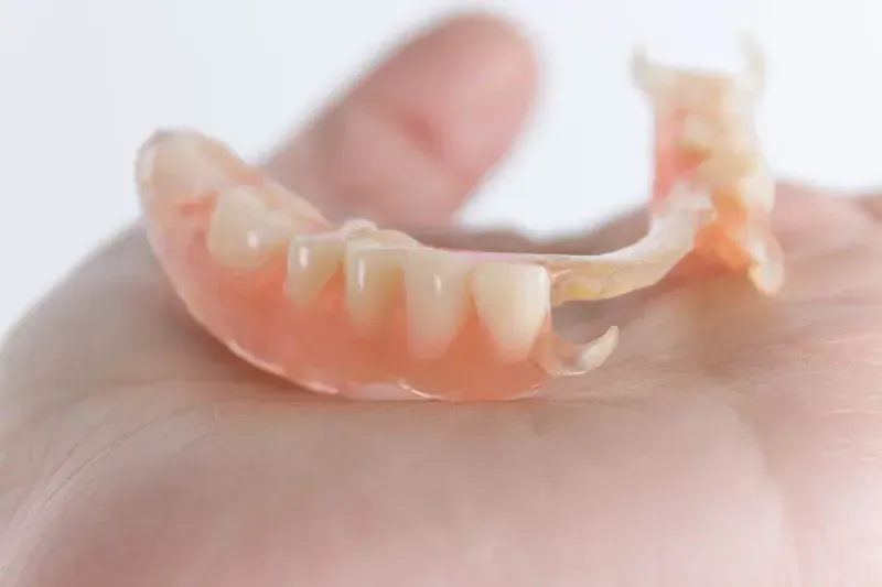 Hand holding Valplast denture